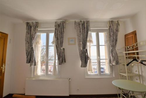 勒克罗图瓦Les Mouettes Blessées的客房设有2扇窗户、窗帘和桌子