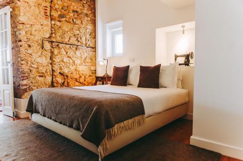 里斯本54圣卡塔琳娜公寓的一间卧室设有一张带石墙的大床