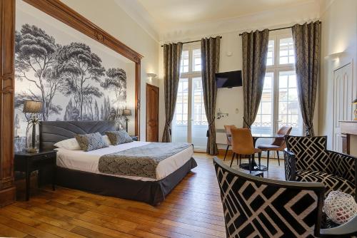 萨尔拉拉卡内达La Villa des Consuls - Gîte de tourisme de charme的卧室配有一张床、一张桌子和椅子