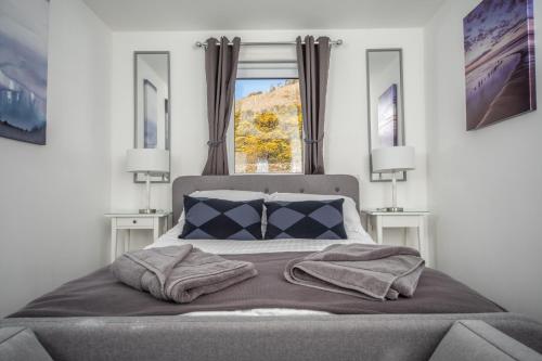蒂恩格Rona@Knock View Apartments, Sleat, Isle of Skye的一间卧室配有一张带两盏灯的床和一扇窗户。