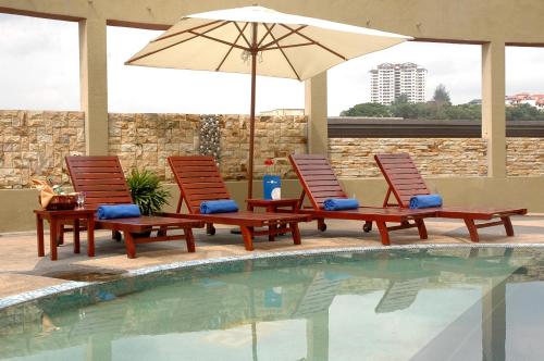 加影东方水晶酒店的游泳池旁的两把椅子和一把遮阳伞