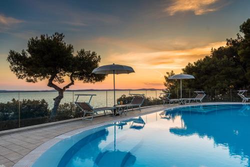 佩特坎内泊尼欧酒店的一个带椅子和遮阳伞的游泳池以及大海