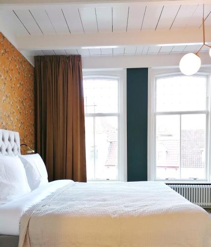 斯滕韦克B&B De Stadssingel的卧室配有白色的床和2扇窗户。