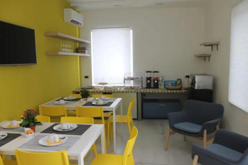 锡拉库扎B&B CaselloA Suites的一间厨房,里面配有两张桌子和黄色椅子