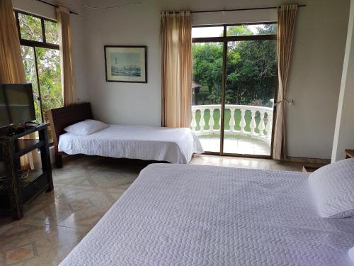 比亚维森西奥Costa del Llano Hotel Campestre的一间卧室设有两张床,窗户设有阳台