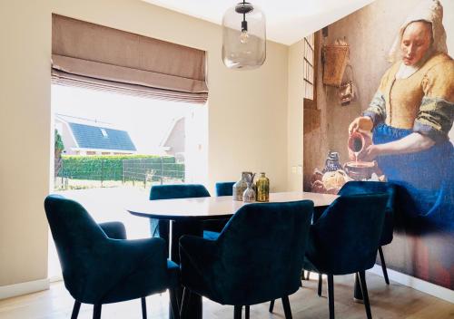 诺德韦克Vakantiehuis Noordwijk的一间带桌椅和绘画的用餐室