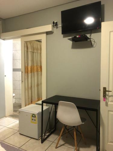 哈博罗内Homey Guesthouse的一张桌子、椅子和墙上的电视