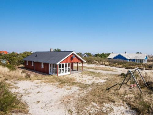 Nørre Lyngvig6 person holiday home in Hvide Sande的海滩上一座红色的房子,屋顶黑