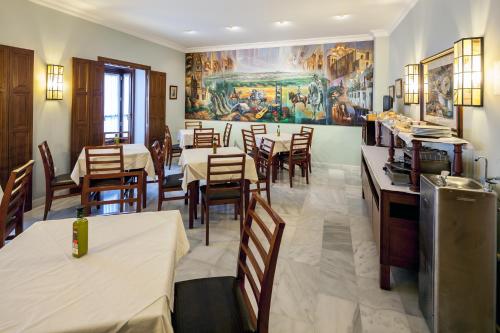 奥苏纳Hotel Las Casas del Duque的餐厅设有桌椅,墙上挂有绘画作品