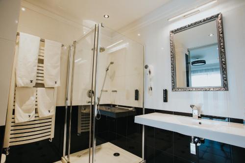 WłoszakowiceHotel Toscania的带淋浴、盥洗盆和镜子的浴室