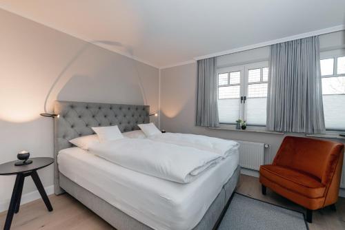 韦斯特兰Jaumann's Südwind Sylt的卧室配有一张白色大床和一把椅子
