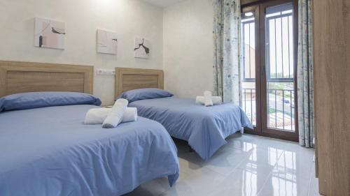 托莱多La casita del caracol by Toledo AP的一间卧室设有两张带蓝色床单的床和窗户。