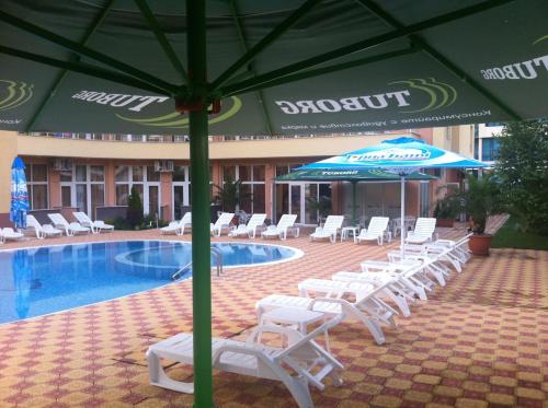 阳光海滩Beatris Family Hotel的一组椅子和遮阳伞,位于游泳池旁