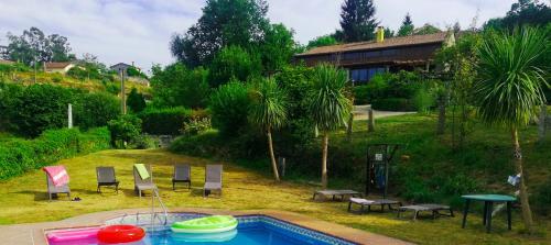 蓬特亚雷亚斯Casa do Val的一个带椅子的庭院和房子的游泳池