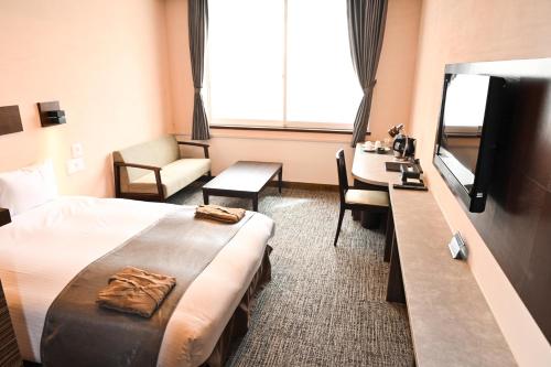 轻井泽轻井泽韦尔久大酒店的酒店客房配有一张床、一张书桌和一台电视。