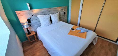 卡马雷Appart'Hôtel du Bout du Monde的卧室配有一张白色大床和木制床头板
