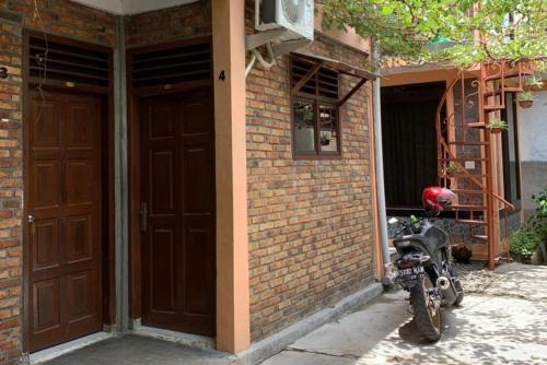 先达KoolKost near Budi Mulia Siantar的停在砖楼旁的摩托车,两扇门
