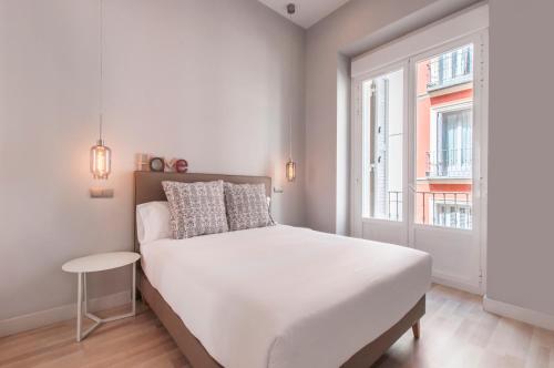 马德里Arenal Suites Gran Vía的卧室配有白色的床和窗户。