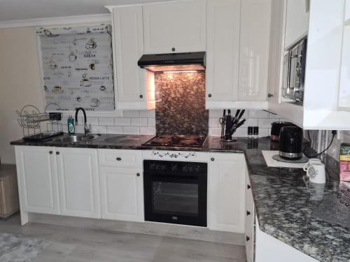 米德兰Cozy Cabin的厨房配有白色橱柜和炉灶烤箱。