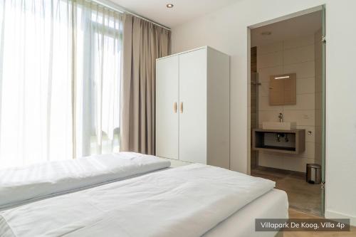 德科赫Villapark De Koog的白色的卧室设有床和大窗户