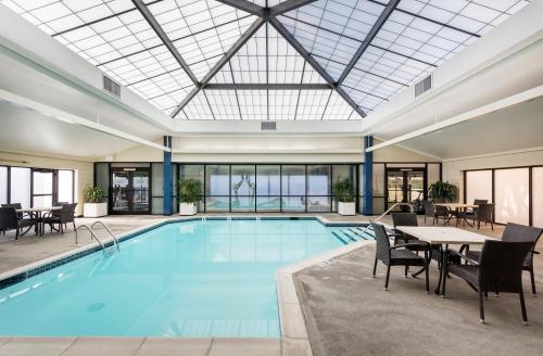 沃里克Crowne Plaza Providence-Warwick (Airport), an IHG Hotel的一个带桌椅的大型游泳池和一个大型玻璃天花板