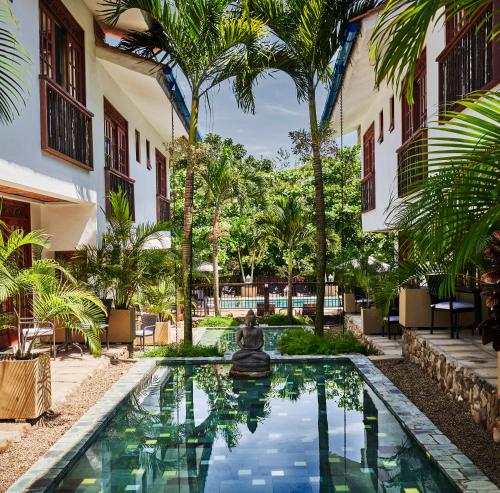 瓜杜阿斯Lombok Hotel & SPA antes Hotel Casablanca的棕榈树建筑庭院中的游泳池