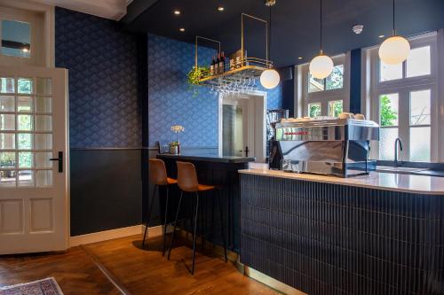 布雷达Boutique Hotel Het Scheepshuys的厨房设有蓝色的墙壁和带凳子的台面。