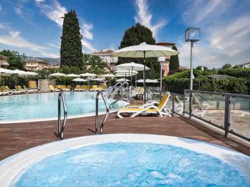 加尔达Hotel Villa Mulino ***S的一个带热水浴池、椅子和遮阳伞的游泳池