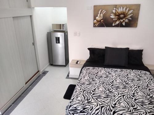 巴兰基亚La Habitación Perfecta的卧室配有黑白床和冰箱。