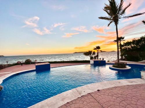 圣卡洛斯Condominios Costa Diamante的日落时分海滩旁的游泳池