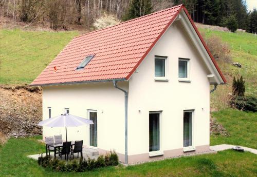 WilhelmsthalFrankenwald Chalets - Ferienhaus Hans的白色的房子,配有桌子和雨伞
