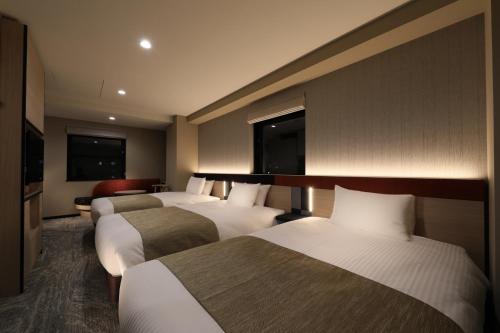 东京Almont Hotel Nippori的酒店客房,设有三张床和一张沙发