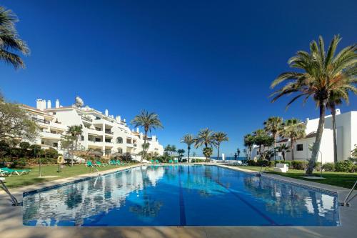马贝拉珊瑚海滩公寓式酒店的一座棕榈树和建筑的大型游泳池
