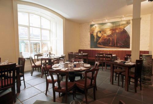 恩尼斯古老土地酒店的餐厅设有桌椅,墙上挂有绘画作品