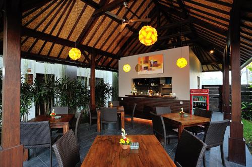 登巴萨恒河酒店公寓 的一间带木桌椅的餐厅和一间酒吧