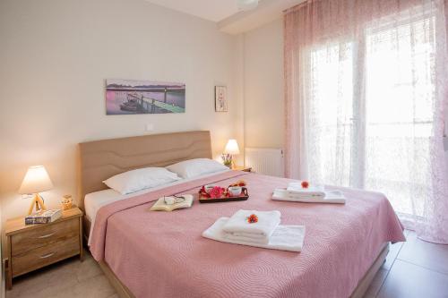 尼亚普拉莫斯Sun & Sea Luxury Apartment的一间卧室配有粉红色的床和2条毛巾