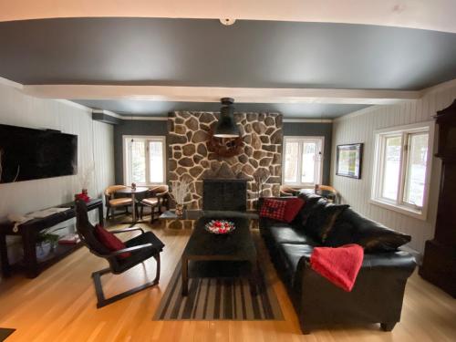 Val-MorinHôtel Far Hills的客厅配有黑色沙发和石制壁炉