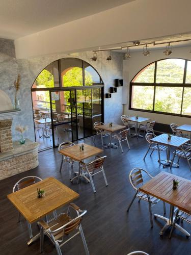 Rogliano尤桑塔涅鲁酒店的餐厅设有桌椅和窗户。