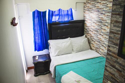 波哥大Hotel Punto 100的一间小卧室,配有一张带蓝色窗帘的床
