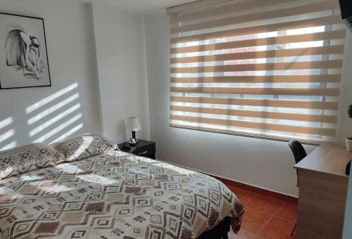 波哥大CASA AVILA - Apartamento amoblado 1 - Villa Alsacia的一间卧室配有一张床和一个带百叶窗的窗户