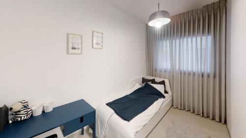 海法Luxury 3&4 Bedroom new apartments - close to the Beach & Bahai Gardens的小房间设有一张床和一张蓝色的桌子