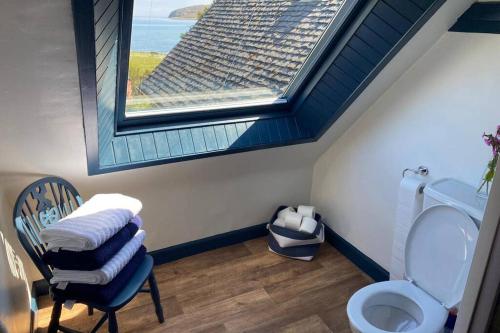 拉姆拉什Lamlash- Self catering accommodation with seaviews的浴室设有窗户和带椅子的卫生间。