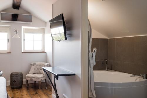 比亚里茨圣朱利安酒店的带浴缸的浴室和墙上的电视