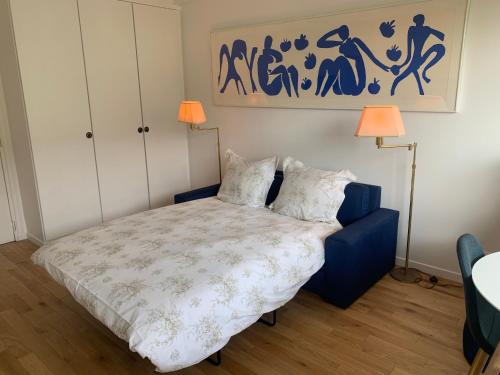 多维尔Deauville Plage - Balcon, Vue Mer & Ville à pied的一间卧室配有一张带两盏灯和一幅画的床铺