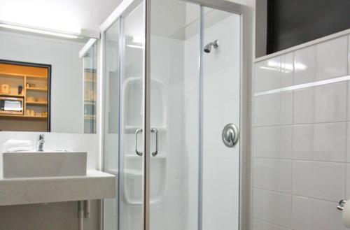 下哈特阿舒尔83号滨海汽车旅馆的带淋浴和盥洗盆的白色浴室