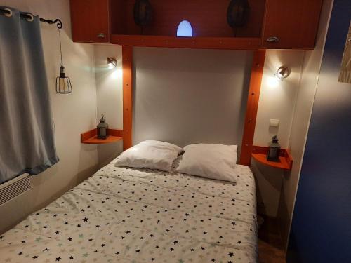 拉波勒Location mobil home的小房间的一个床位,配有两个枕头