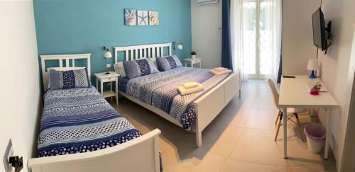 卡斯特拉玛雷帝斯达比亚MareLuna b&b的卧室设有两张床铺、蓝色的墙壁和书桌