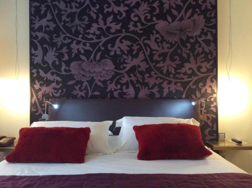 多勒Hotel La Chaumiere的一间卧室配有一张带红色枕头的大床