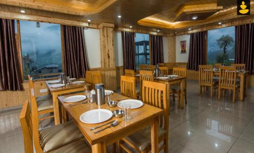 马拉里LivingStone Manali的餐厅设有木桌、椅子和窗户。