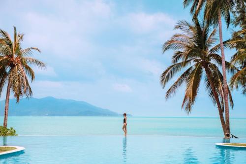 曾蒙海滩Melati Beach Resort & Spa的站在棕榈树度假村水中的女人
